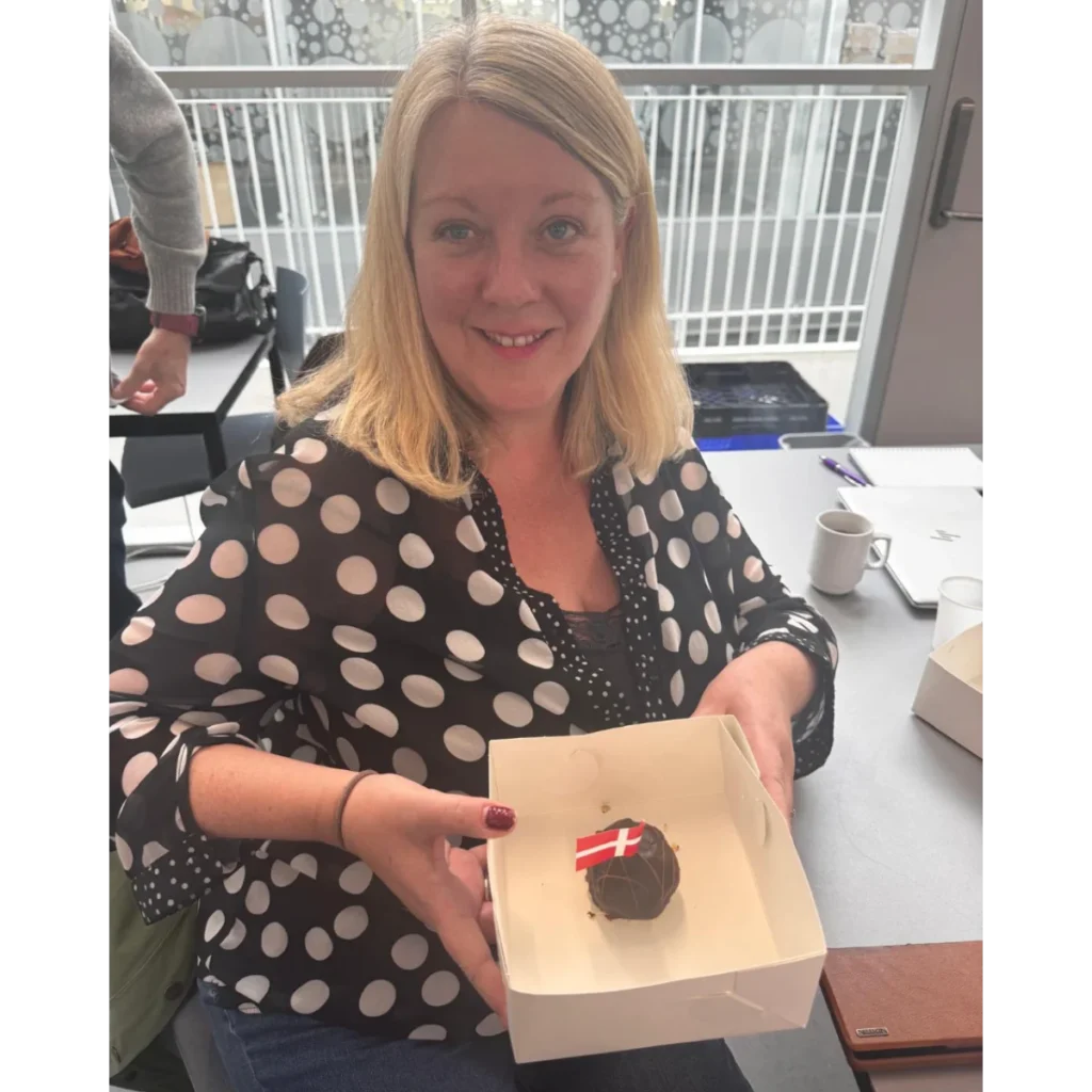 Photo of Marilyn Lennon holding a birthday cake at the AICE meeting in Denmark