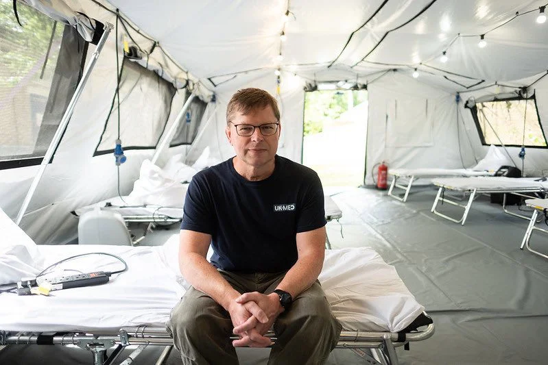 Photo of Professor Angus Watson OBE sitting on a bed in a hospital